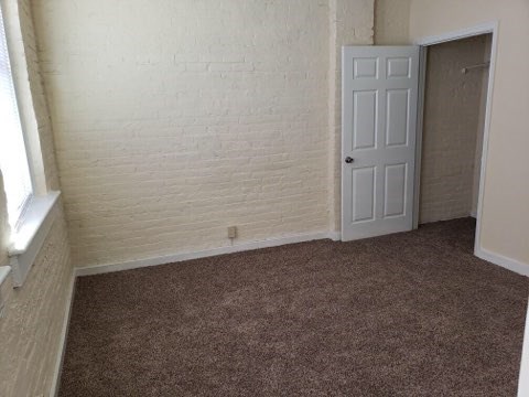 an empty room with a white door and a brown carpet